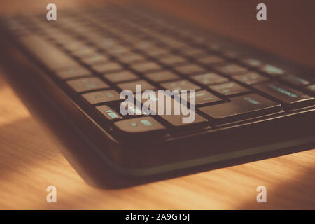 Clavier noir sur la table en bois brun, vue de côté. Banque D'Images