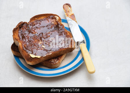 Marmite sur pain grillé sur une plaque sur fond blanc Banque D'Images