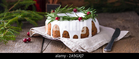 Gâteau aux fruits de Noël traditionnels faits maison sur le fond en bois avec des branches de sapin, décoré par les canneberges et romarin, avec un copyspace Banque D'Images