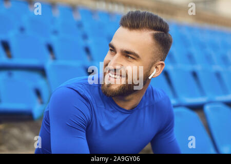 Un gars en sportswear est assis dans le stade après la formation. Banque D'Images