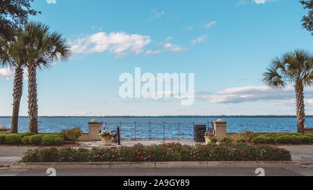 Des bancs au bord de l'eau dans un parc sur le lac Monroe au centre-ville de Sanford, Floride. Banque D'Images