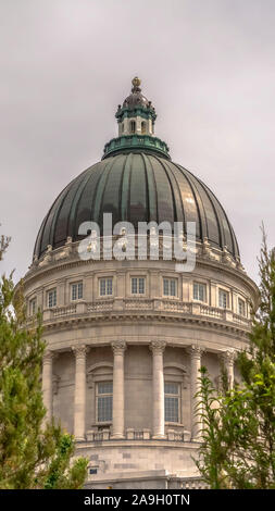 Châssis vertical célèbre Utah State Capitol Building dome encadrées avec des arbres contre ciel nuageux Banque D'Images