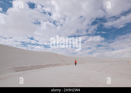 L'homme dans des vêtements décontractés au milieu de dunes de sable blanc contre le ciel bleu Banque D'Images