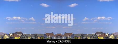 Maisons colorées en bleu ciel au-dessus de la communauté et peu de nuages gonflés blanc Banque D'Images