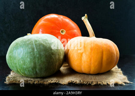 Trois citrouilles de différentes couleurs sur un fond noir. Banque D'Images