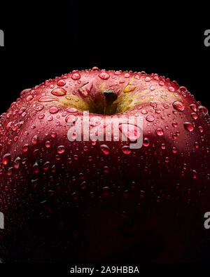 Pomme Rouge avec de grandes gouttes d'eau. La photo en gros plan. Fond noir. Banque D'Images