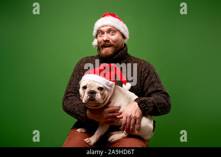 Homme et chien dans santa caps sur fond vert en studio vide Banque D'Images