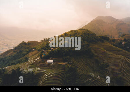 Belle Vue aérienne du lever du soleil sur les rizières en terrasses de Sapa au Vietnam du Nord au cours de l'automne comme les nuages passent sur les sommets des montagnes Banque D'Images