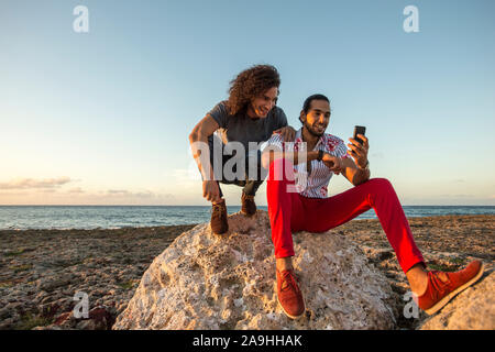 Deux amis avec téléphone mobile sur la plage Banque D'Images