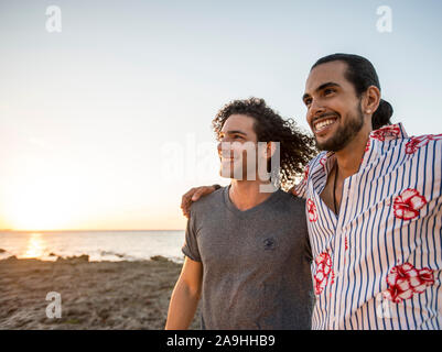 Deux amis marchant sur la plage pendant le coucher du soleil Banque D'Images