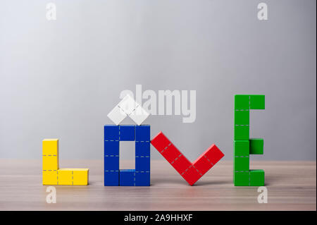 Puzzle en bois coloré jouet en bois, blocs de construction avec des formes géométriques. Le mot amour Banque D'Images