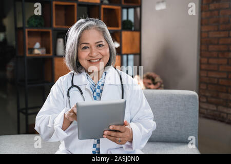 Sourire pendant l'utilisation de tablet pédiatre Banque D'Images