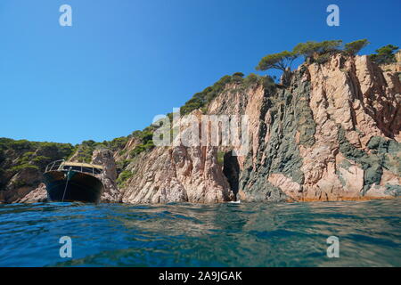 Falaise côtière rocheuse avec un bateau vu de surface de la mer, Espagne, Méditerranée, Costa Brava, Catalogne, Aigua Xelida, Palafrugell Banque D'Images