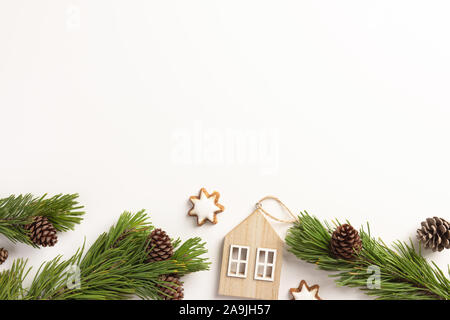 Composition de Noël. Branches d'épinette avec de petites maisons en bois, sur un fond blanc. L'hiver, Noël concept. Mise à plat, vue du dessus. Banque D'Images