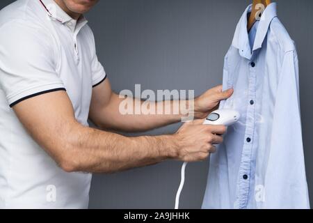 Portrait d'un homme bleu chemise en utilisant la vapeur cuiseur vapeur électrique Banque D'Images