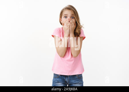 Les jeunes en difficulté peur cute blonde petite fille appelant à l'aide, paniquée, se sentent effrayés halètement choqué couvrir la bouche avec palmiers, peur contrarié de l'appareil photo Banque D'Images