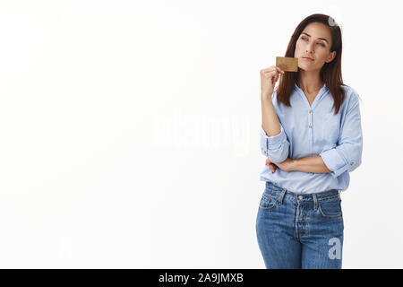 Sly intrigué bon-à la femme d'âge moyen, hideux ont quelque chose d'intéressant à l'esprit, maintenir smartphone, le regard pensif, sourire, savoir comment Banque D'Images