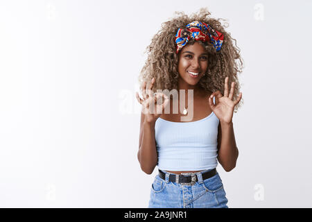 Optimiste, convaincu africains-américains aux cheveux bouclés blonds hipster girl avec serre-tête élégant, souriant, heureux de recommander bonne affaire, voir d'accord, ok sign, sm Banque D'Images