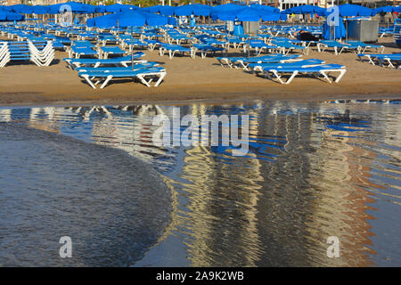 Les chaises longues et parasols sur la plage Levante, reflétée sur le sable humide en début de matinée, Benidorm, Alicante Province, Espagne Banque D'Images