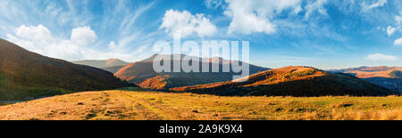 Superbe vue panoramique sur la crête de la montagne en automne. paysage magnifique avec les collines et les prairies dans l'herbe. ensoleillé avec nuages moelleux Banque D'Images