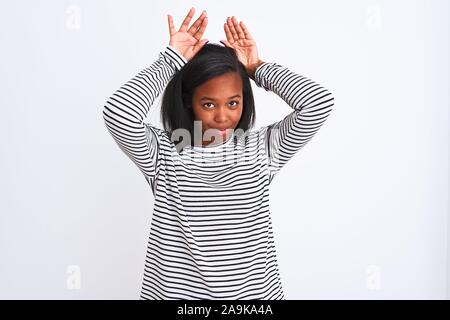 Beau young african american woman wearing winter sweater sur fond isolé faisant Bunny Ears geste avec les mains paumes à cyniques et s Banque D'Images