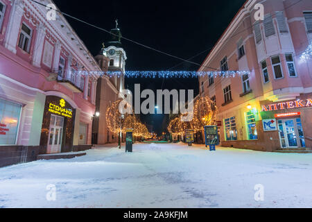Uzhgorod, Ukraine - 06 jan 2019 : nuit d'hiver en ville. superbe illumination de noël bleu et jaune vide. Voloshyna street couvertes de neige. cath Banque D'Images
