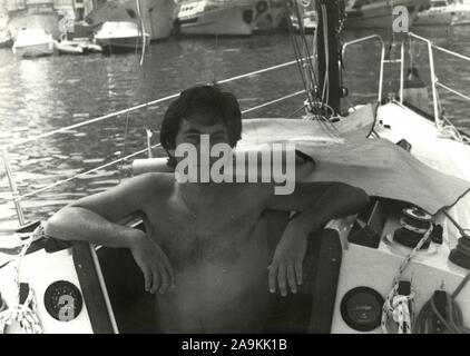 Un garçon sur un bateau à voile dans le port, Italie Banque D'Images