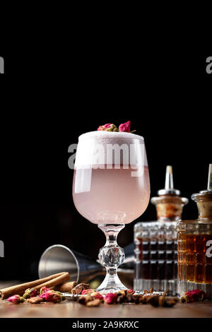 Cocktail rose femelle avec de la mousse dans un verre. décorées de rose séchée. dans l'arrière-plan est visible inventaire barman Banque D'Images