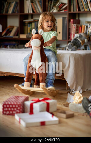 Petit garçon mignon cheval Cheval à bascule en bois in front of Christmas Tree Banque D'Images