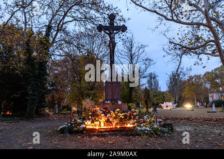 Une tombe avec une croix couverte de bougies sur la Toussaint à l'avance du Jour des morts dans le cimetière Kerepesi de Budapest Banque D'Images