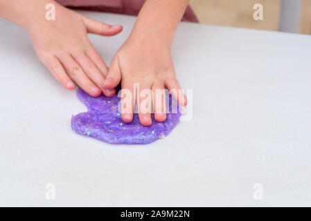 Processus de mucus. Purple glitter magic slime sur un fond blanc. Slime froisse l'enfant. Close up of hands. Banque D'Images