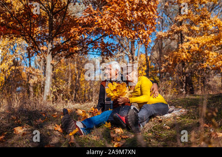 Saison d'automne de plaisir. Senior couple hugging assis dans un parc. Man and Woman relaxing outdoors Banque D'Images