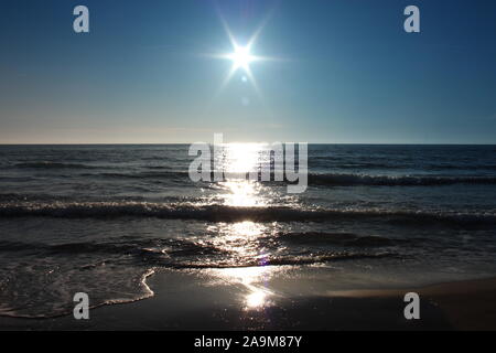 Le soleil se couche sur la mer au coucher du soleil, à l'horizon, il ressemble à un fake star. La mer est calme en face d'une plage de sable fin de la Versilia, Toscane, Italie Banque D'Images