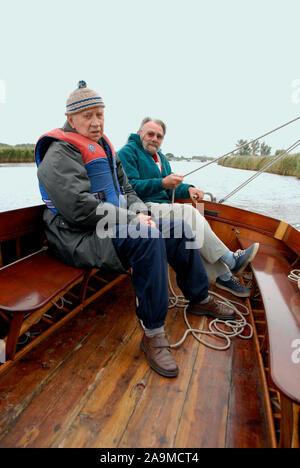 Deux hommes âgés d'une petite voile canot ouvert par mauvais temps, Norfolk, Angleterre Banque D'Images