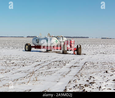 Le remplissage des réservoirs d'ammoniac anhydre et wagon dans les champs agricoles de soja récolté couvertes de neige après une tempête de neige au début de l'hiver Banque D'Images