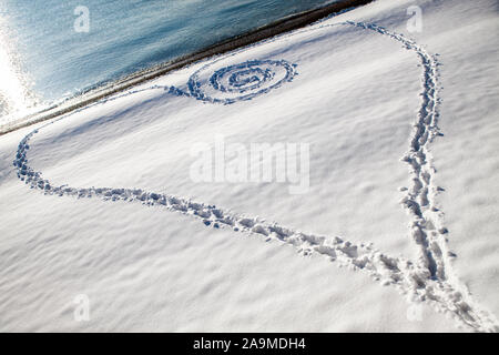 Forme de coeur fait à partir de traces de pas dans la neige sur prinstine beach. Banque D'Images