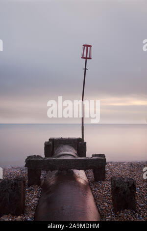 Tuyau d'eau de l'exutoire et marqueur sur plage, Bexhill on Sea, East Sussex, UK - longue exposition Banque D'Images