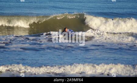 Par surfeur mâle une vague déferlante dans la mer du Nord sur une après-midi l'hiver. Aberdeen, Écosse, Royaume-Uni. Banque D'Images