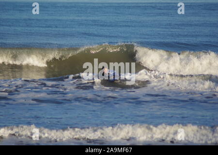 Par surfeur mâle une vague déferlante dans la mer du Nord sur une après-midi l'hiver. Aberdeen, Écosse, Royaume-Uni. Banque D'Images