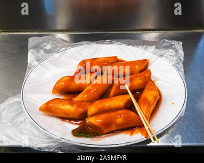 La cuisine Coréenne - partie de tteokbokki (Stir-fried gâteau de riz) dans la sauce épicée au marché local de la ville de Séoul Banque D'Images