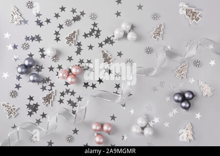 Noël arrière-plan avec gris pastel pink glitter balls, stars, sur fond gris argent. Vue d'en haut. Motif de Noël. Nouvelle Année. Banque D'Images