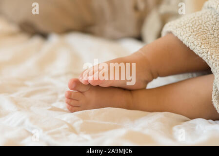 Mignon bébé pieds enveloppés dans une couverture. Concept de famille heureuse. Matin à la maison confortable. Image tonique, selective focus mis sur pieds. Banque D'Images