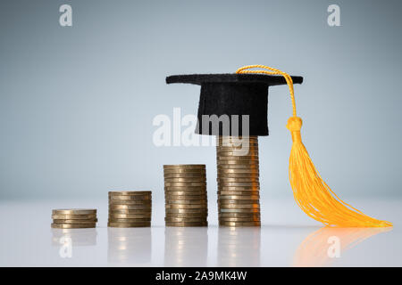 Miniature de Graduation Hat sur le dessus de la pile de pièces de bureau réfléchissant Banque D'Images