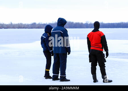 Les sauveteurs en uniforme et combinaison de plongée sont en service sur la glace d'une rivière gelée en hiver, la pêche et des manifestations sportives. Sauvetage Banque D'Images