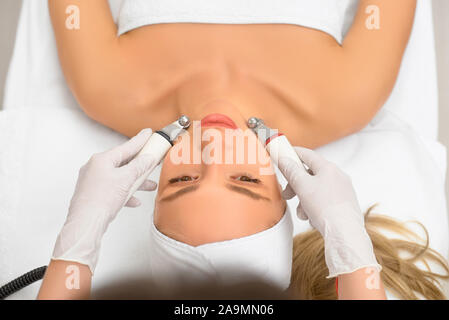 Femme close up recevoir massage du visage microdermabrasion électrique sur l'équipement de salon de beauté. rf procédure de levage dans un salon de beauté. Vue d'en haut Banque D'Images