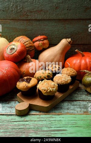 Accueil de cuisson ou hygge concept. Muffins à la citrouille imparfaite et les courges d'hiver lumineux sur fond de bois minable copie espace. Still Life with low key cop Banque D'Images