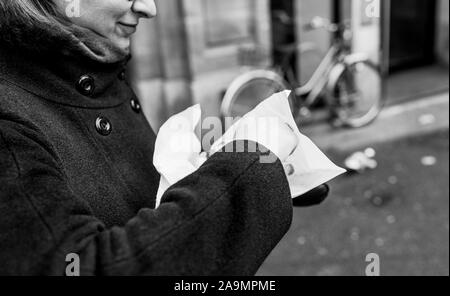 Vue latérale du woman eating regardant la tarte alsacienne traditionnelle avec de la viande de porc dans le centre de Strasbourg pendant les vacances d'hiver - image en noir et blanc Banque D'Images