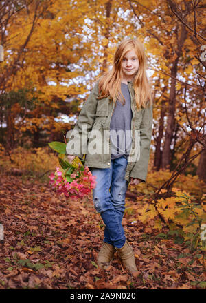 Red HAIRED GIRL holding Flowers à l'automne Woods Banque D'Images