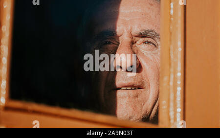 Un homme âgé en regardant par la fenêtre. Banque D'Images