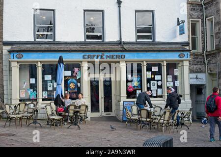 Les gens assis à l'extérieur du Caffe Nero en marché, Kendal, Cumbria sur une journée froide Banque D'Images